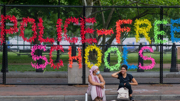 A sign made out of confetti that reads "Police Free Schools" on a gate during a Black Lives Matter protest.