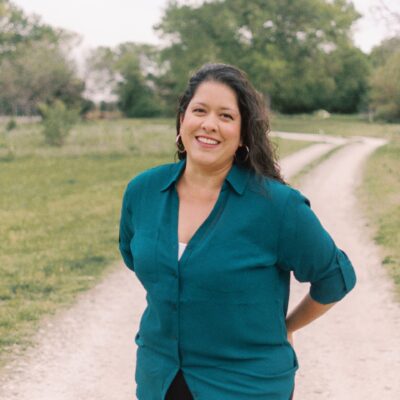 shanna stands with her arms behind her back smiling