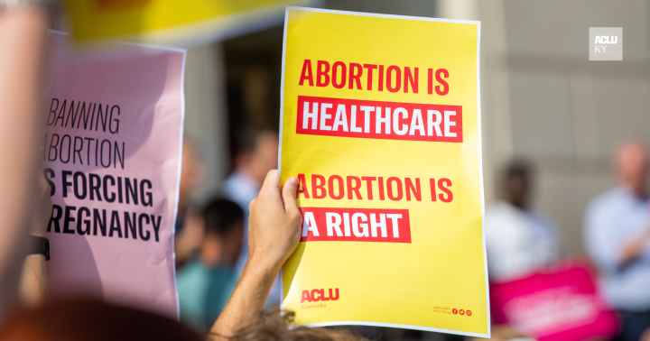 Person holding yellow protest sign that reads "Abortion is Healthcare. Abortion is a right."