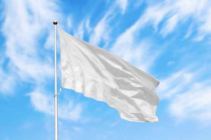 A white flag flies over blue skies in background.