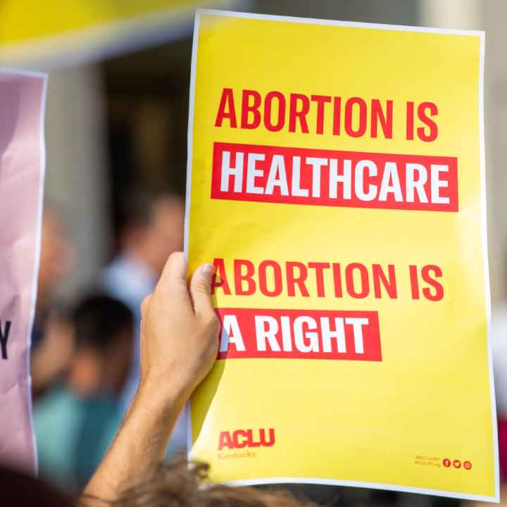 Person holding yellow protest sign that reads "Abortion is Healthcare. Abortion is a right."